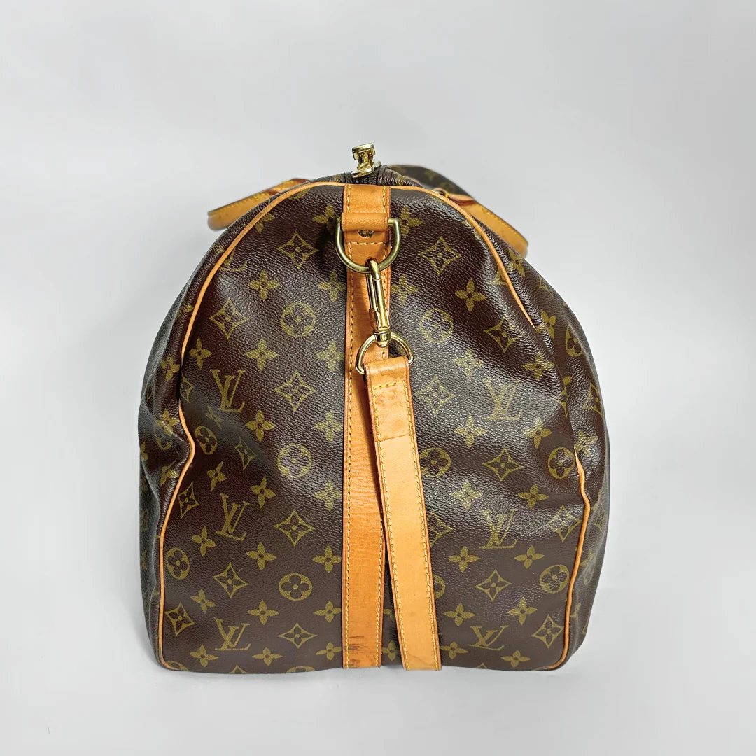 Brown leather bag with gold monogram pattern on a light gray background