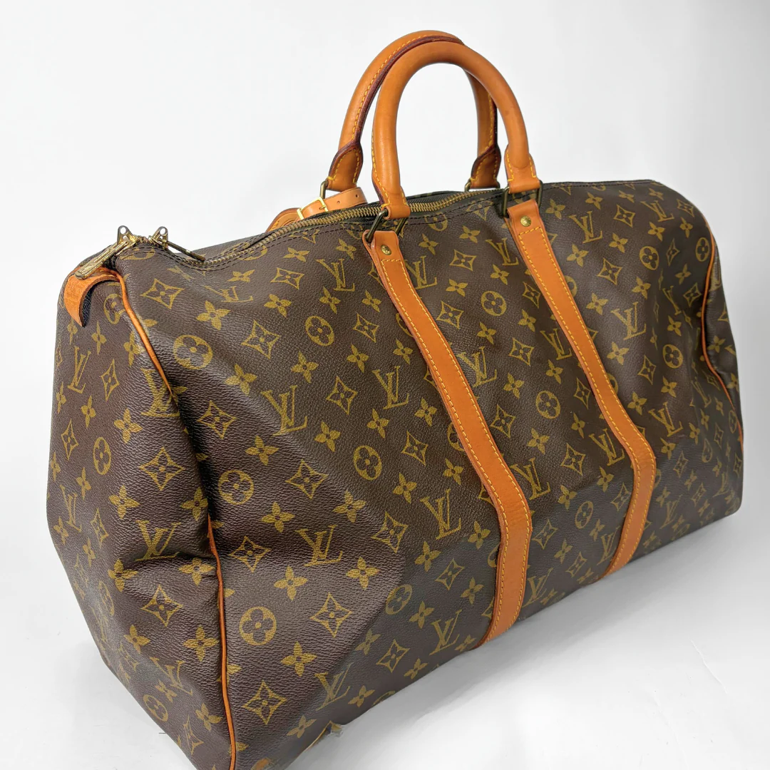 Brown hand bag with orange accents and a prominent logo pattern on a white background