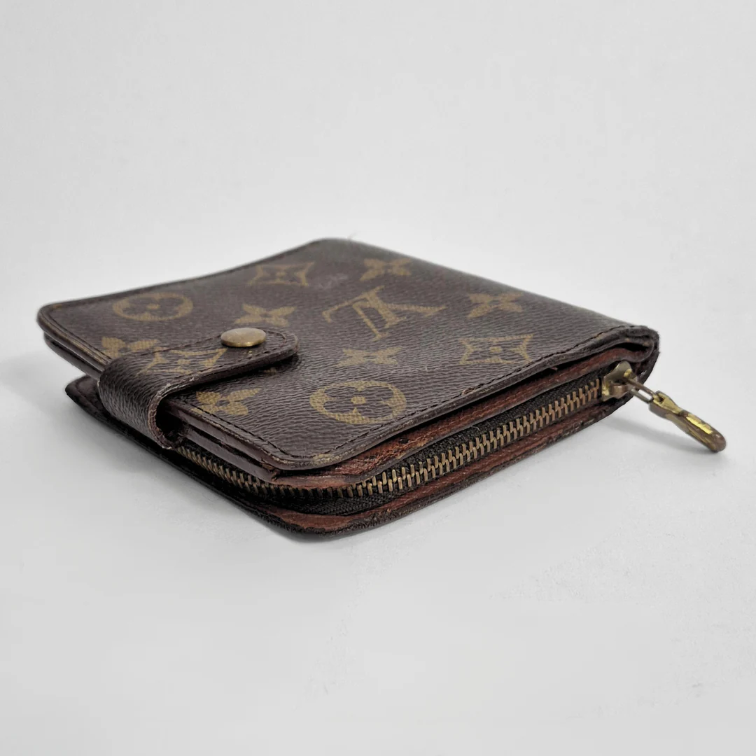 Brown wallet with gold monogram pattern on a light gray background