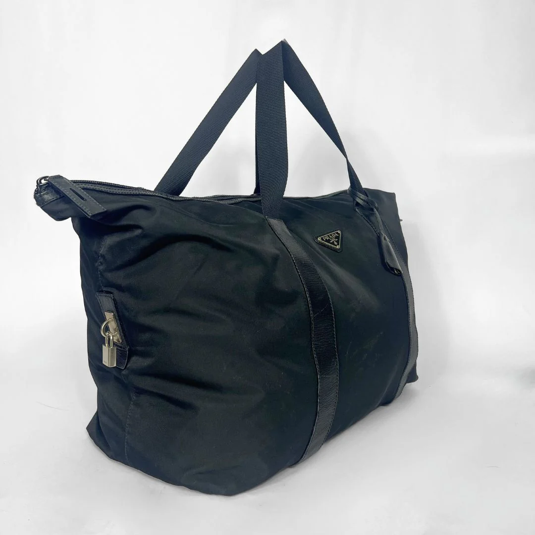 Black tote bag with a visible brand logo on a white background