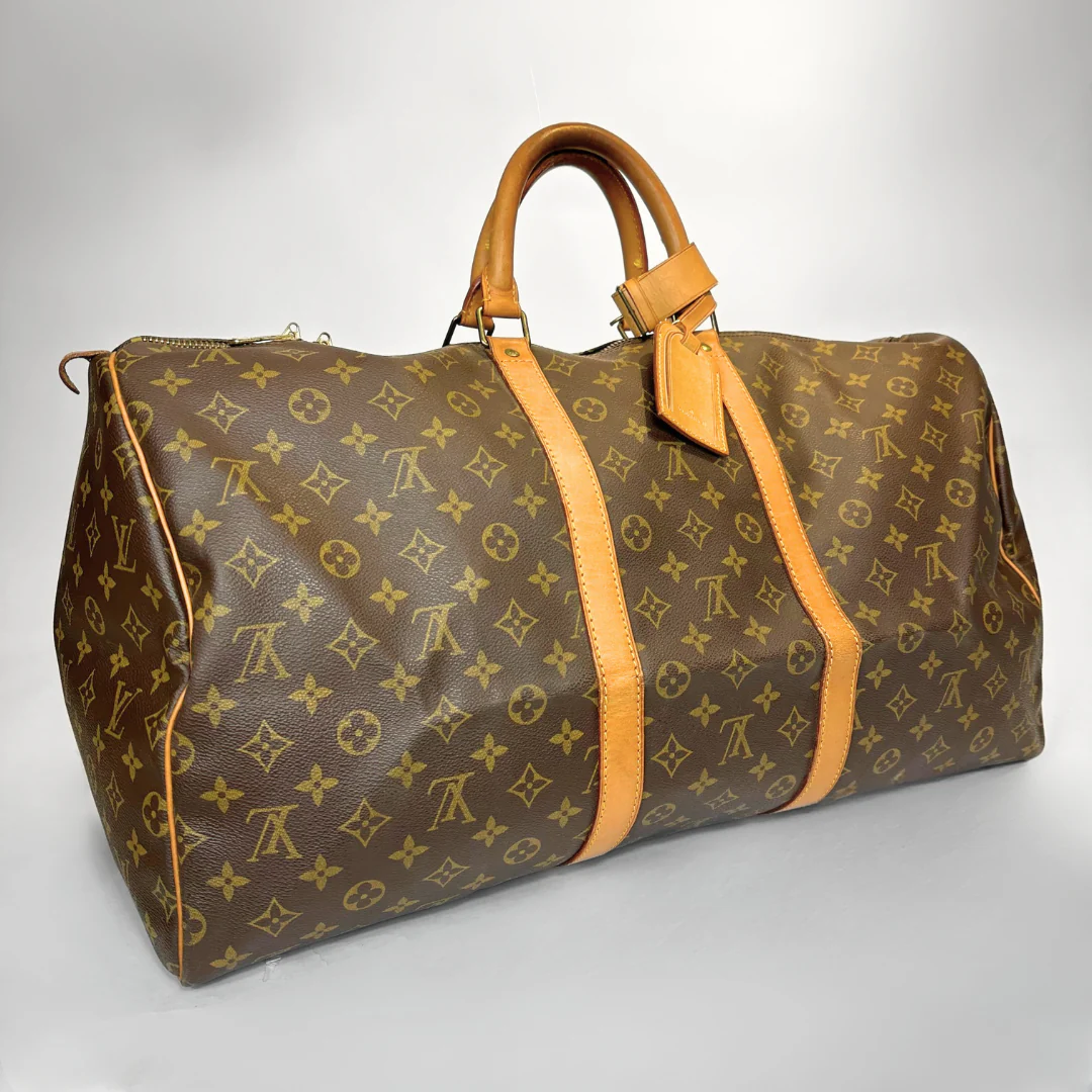 Brown travel bag with yellow monogram pattern on a light gray background