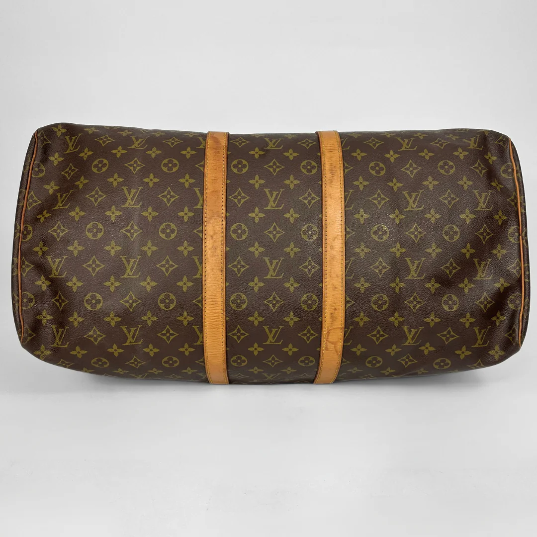 Brown monogram patterned bag with wooden accents on a white background
