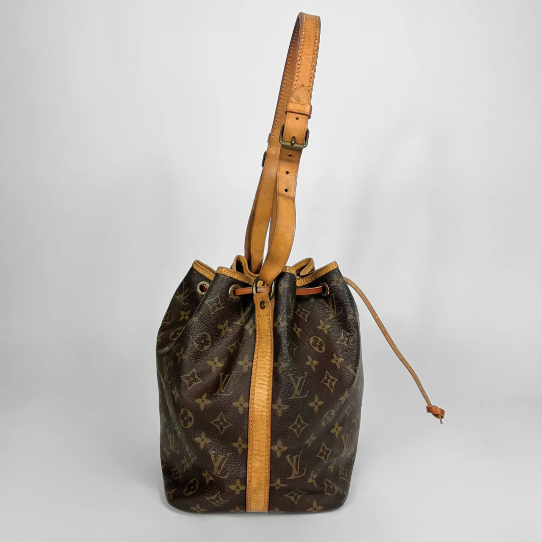 Brown monogram handbag with tan leather strap on a light gray background
