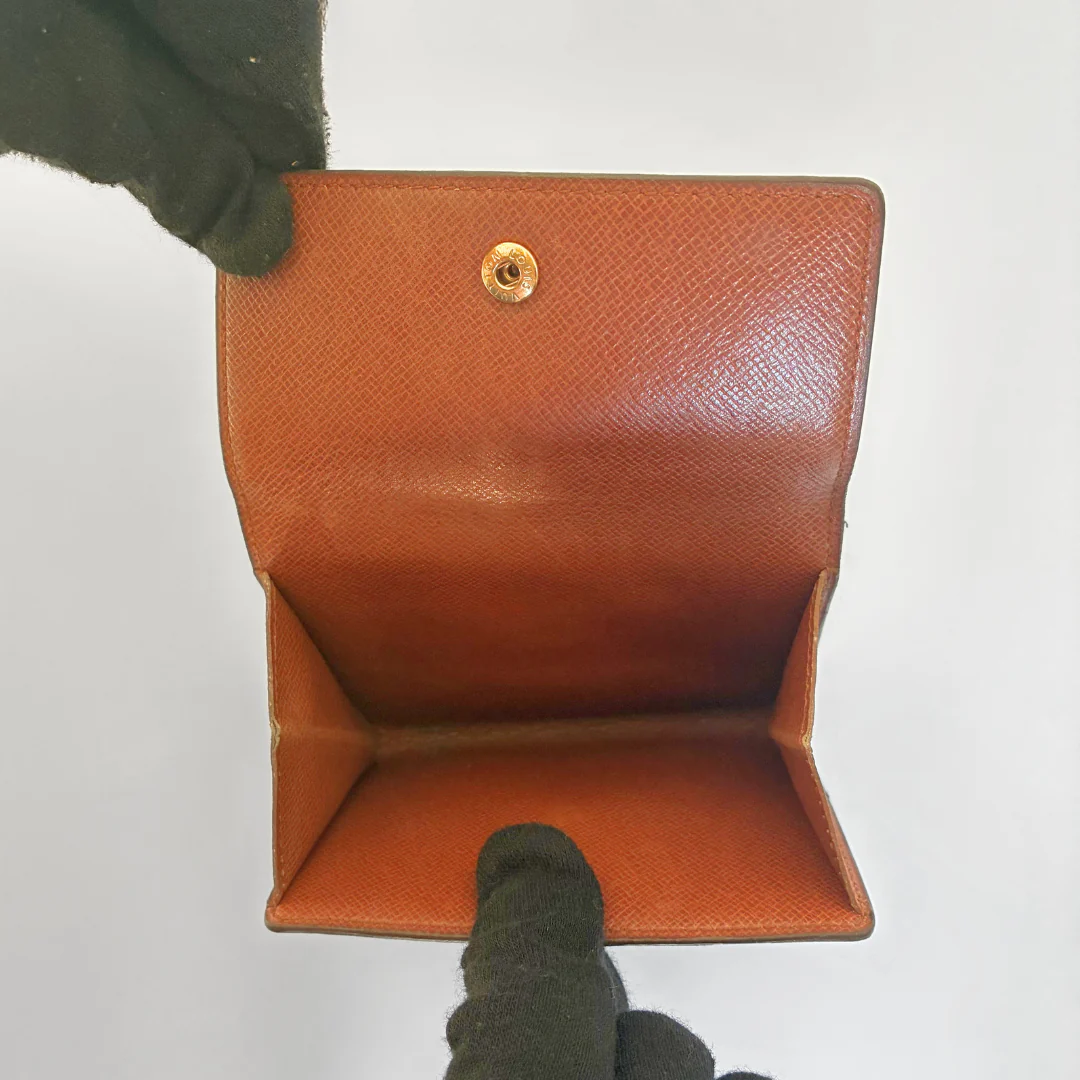 Brown leather wallet held by a gloved hand on a white background