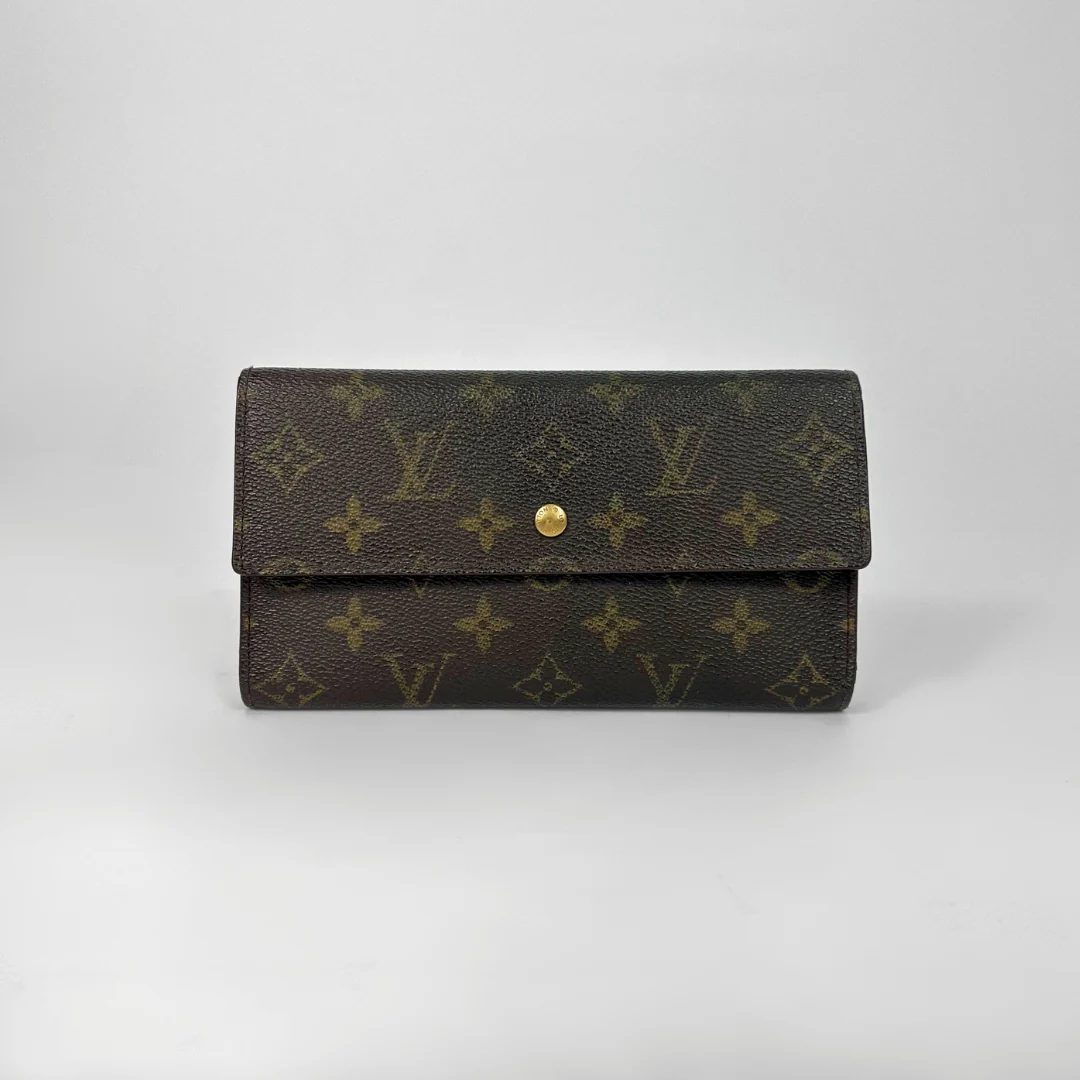 Brown wallet with gold monogram pattern on a light gray background