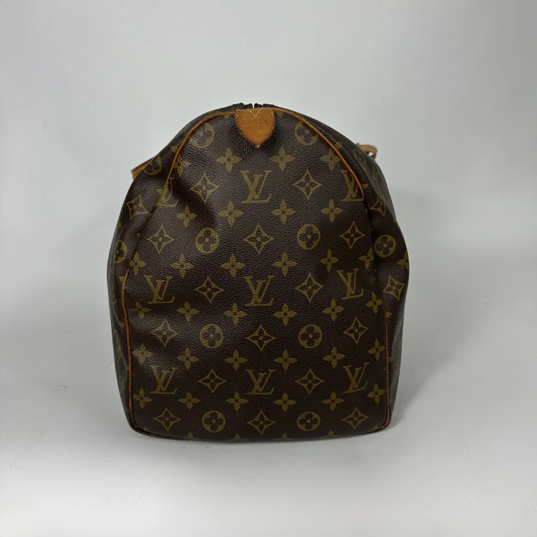 Brown monogram patterned duffel bag with tan leather straps on a white background