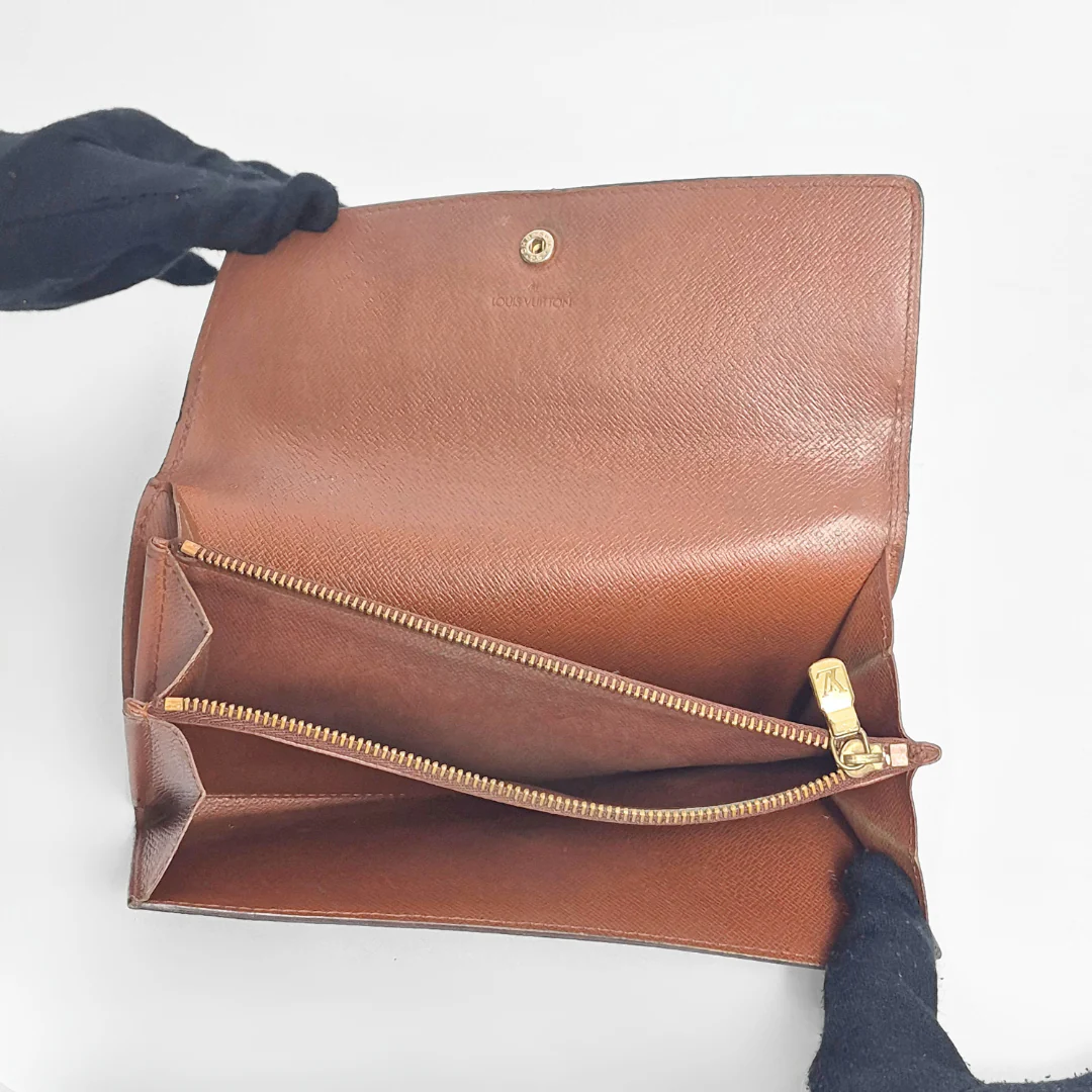 Brown leather handbag with gold zipper on a white background