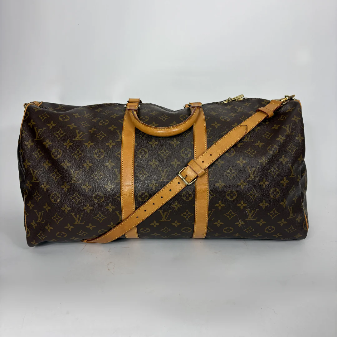 Brown monogram duffel bag with tan leather straps on a white background