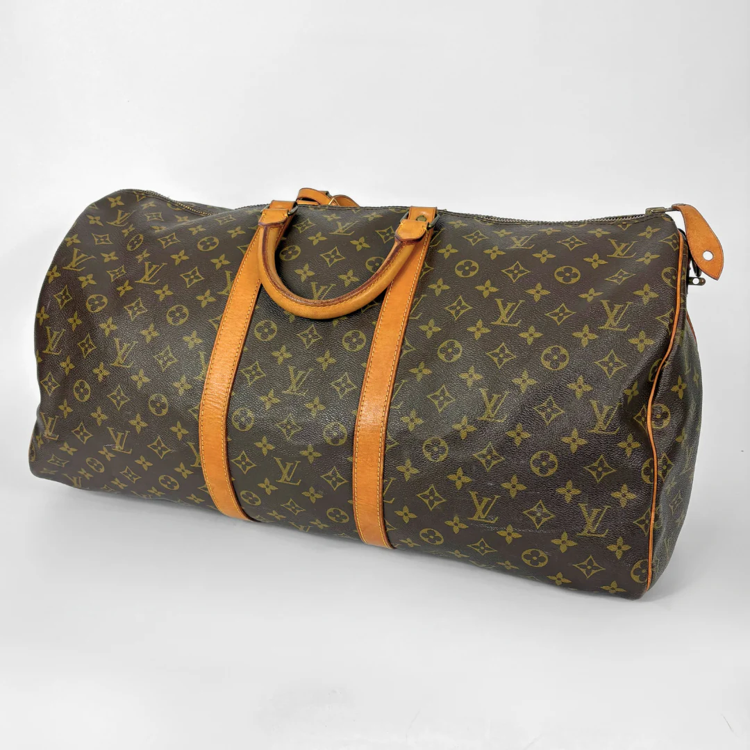 Louis Vuitton monogram travel bag with brown handles on a white background