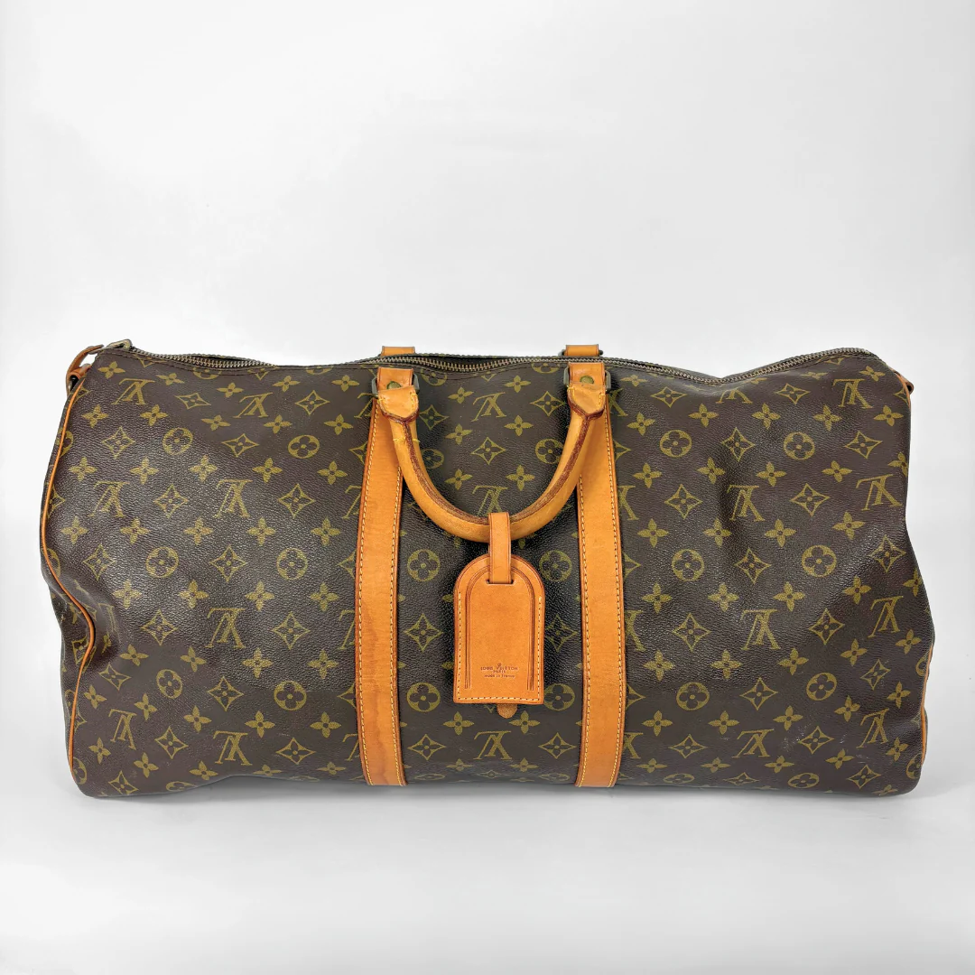 Louis Vuitton monogram travel bag with brown handles on a white background
