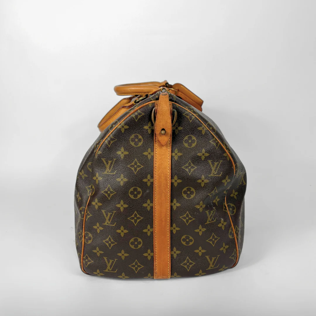 Louis Vuitton monogram travel bag with brown handles on a white background
