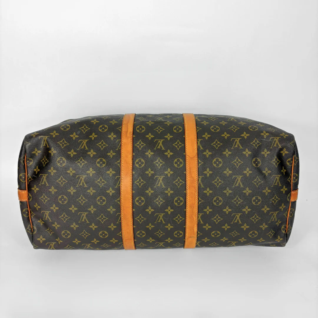 Louis Vuitton monogram travel bag with brown handles on a white background