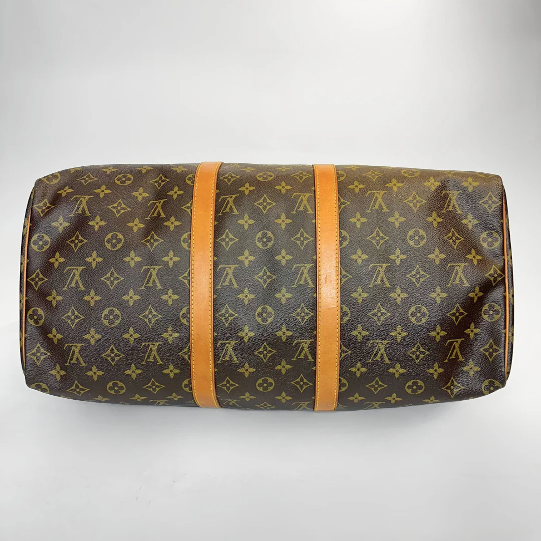 Brown travel bag with monogram pattern on a white background