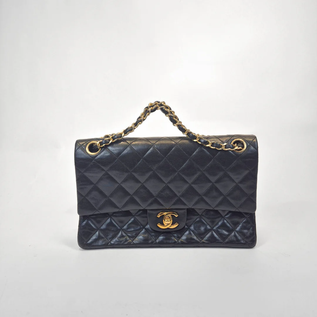 Black Chanel handbag with gold chain handle and clasp on a white background