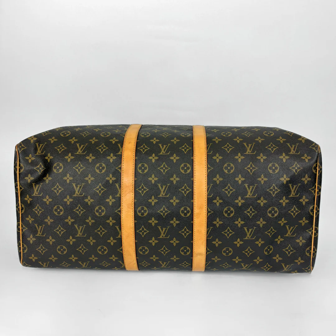 Louis Vuitton monogram duffel bag with tan straps on a light gray background