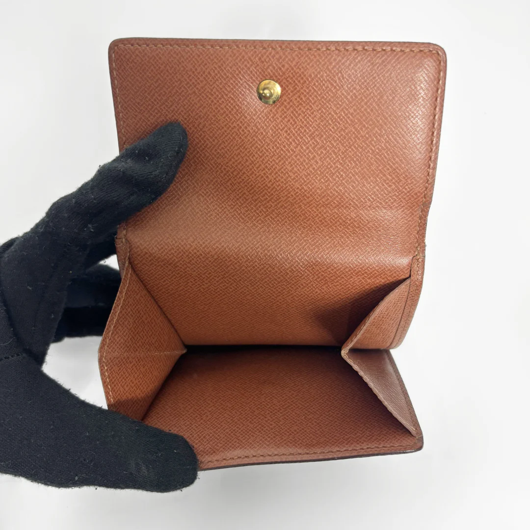 Brown leather wallet with a gold button held by a black-gloved hand on a white background