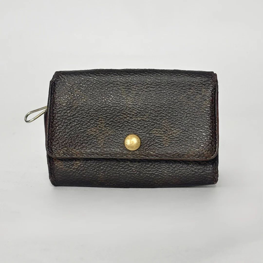 Black leather wallet with a gold button on a light gray background