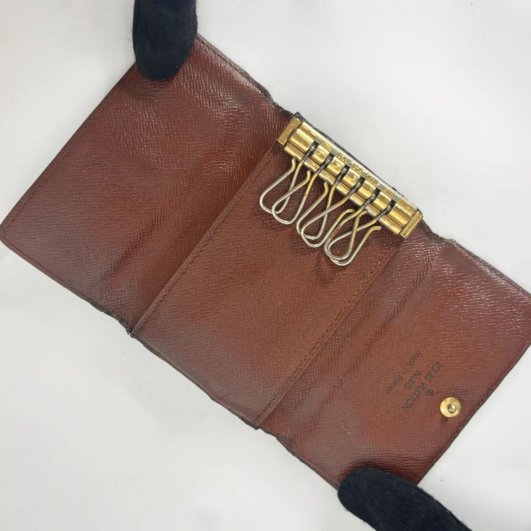 Brown leather wallet with gold keychain on a white background