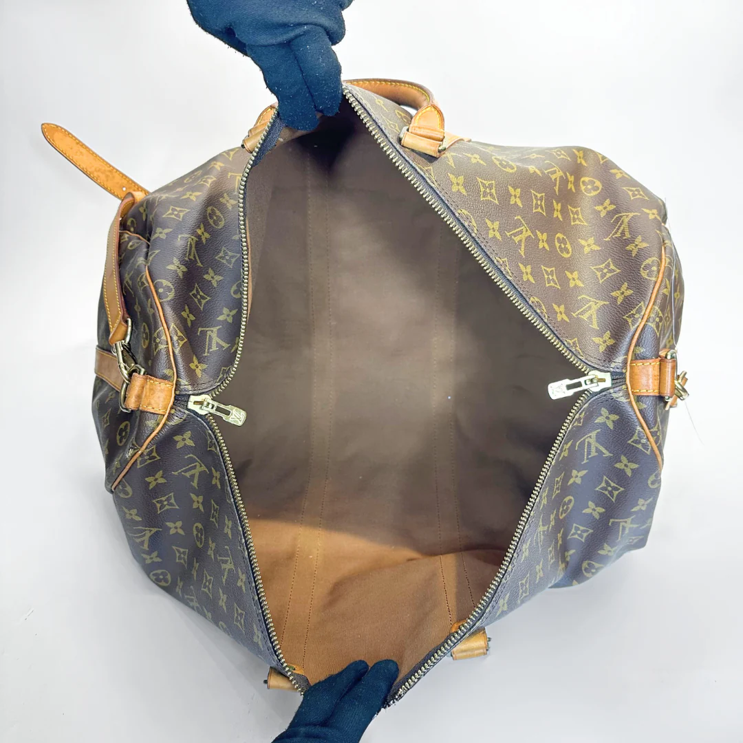 Louis Vuitton monogram bag with a hand opening it on a white background