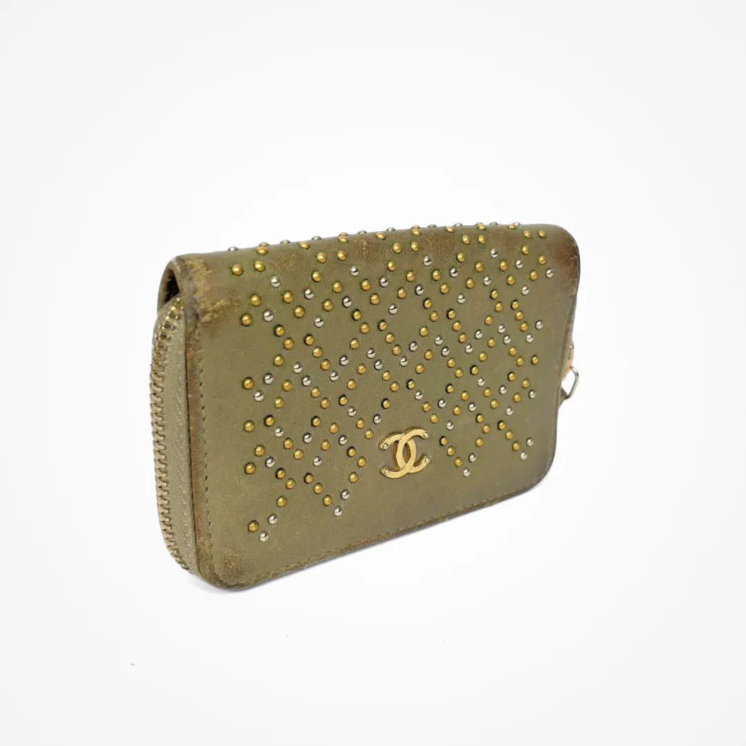 Beige Chanel wallet with gold studs on a white background