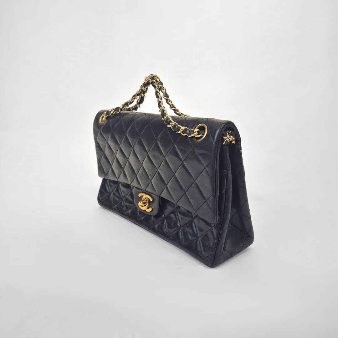 Black Chanel handbag with gold chain handle and clasp on a white background