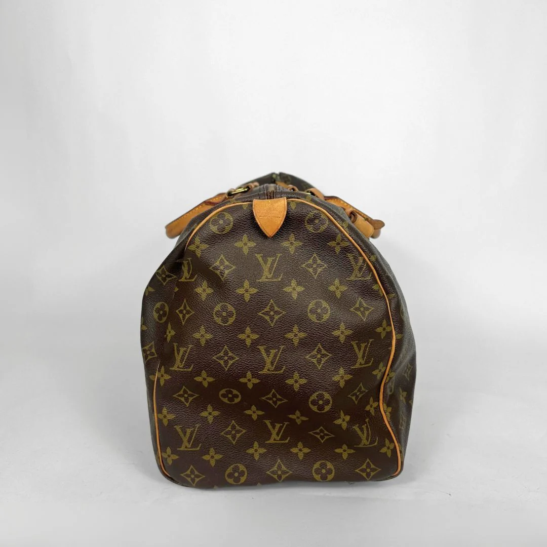 Brown monogram duffel bag with tan leather handles on a white background