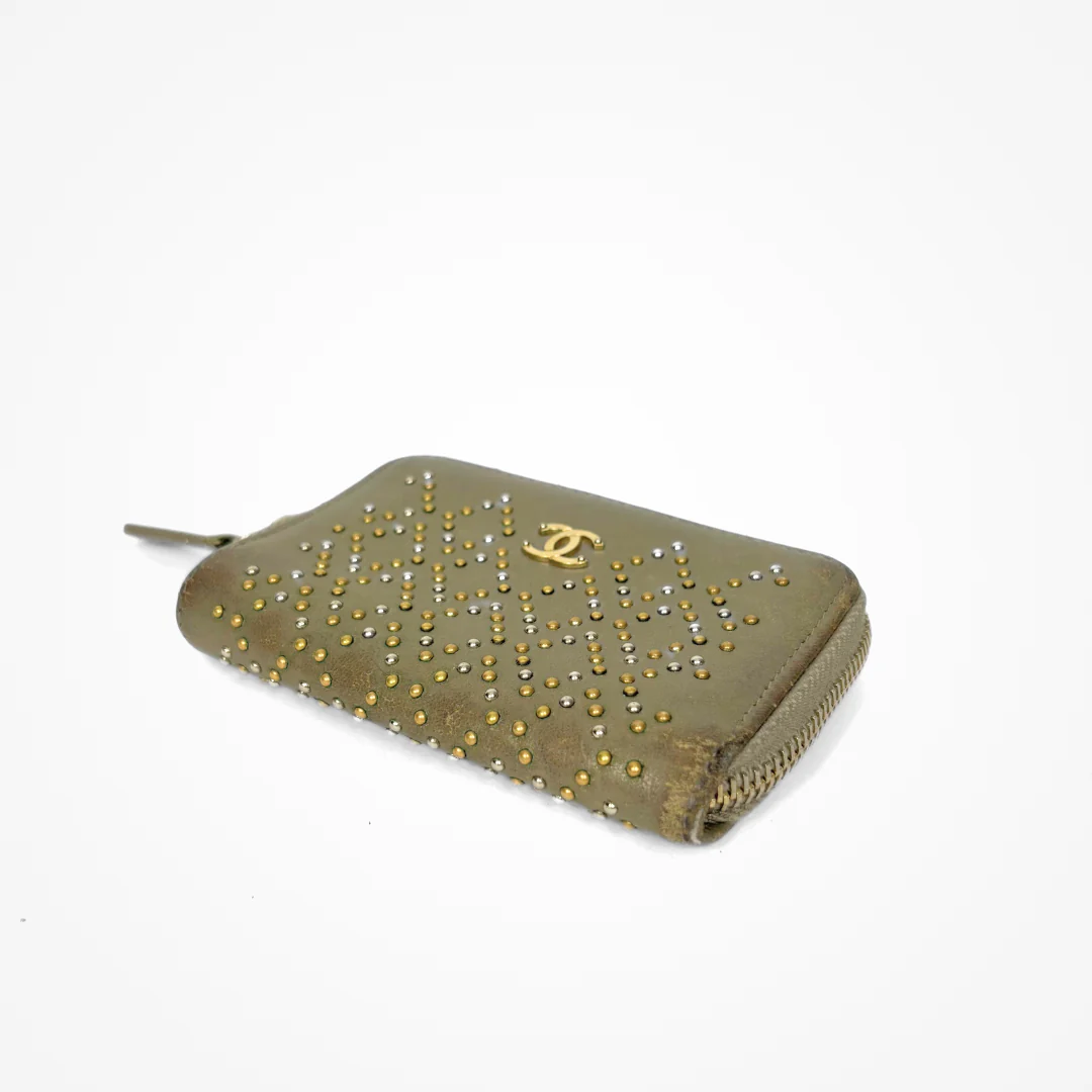Beige Chanel wallet with gold studs on a white background