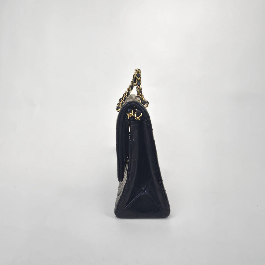 Black Chanel handbag with gold chain handle and clasp on a white background
