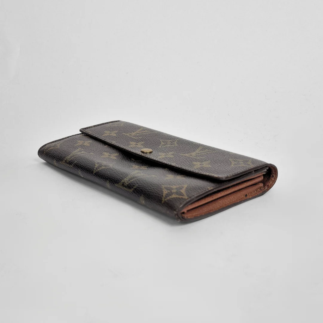 Designer wallet with monogram pattern on a light gray background