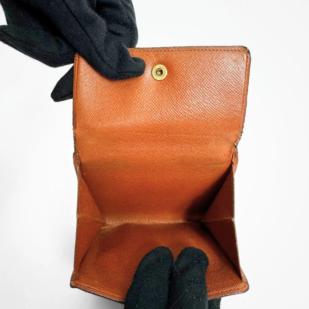 Brown leather wallet held by a gloved hand on a white background