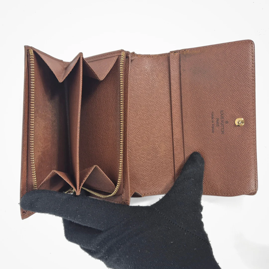 Brown leather wallet held open by a black-gloved hand on a white background