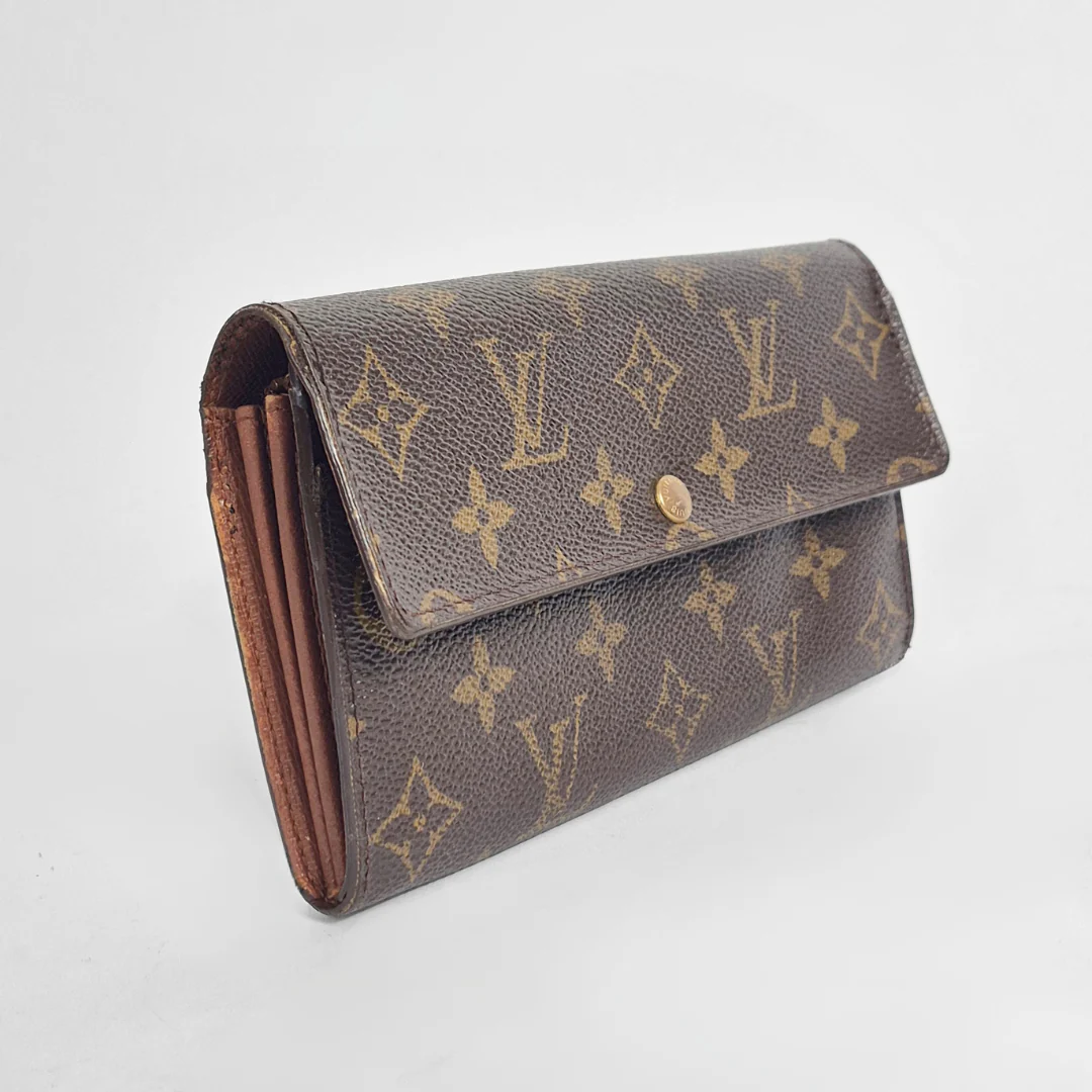 Louis Vuitton wallet with monogram pattern on a light gray background