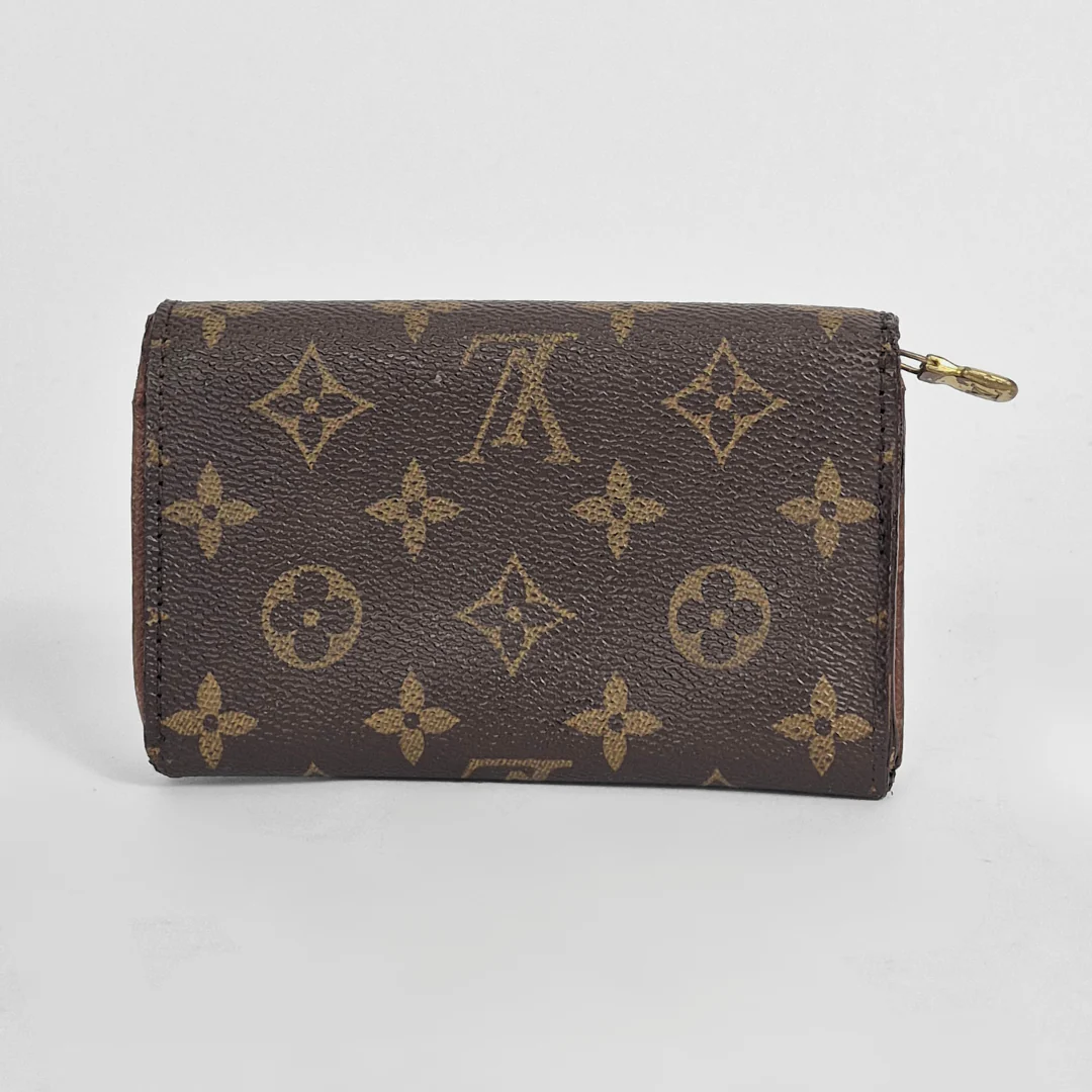 Brown wallet with gold monogram pattern on a light gray background