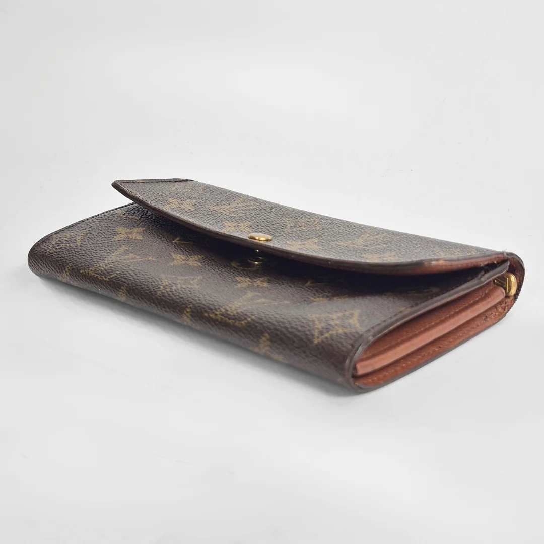 Brown wallet with monogram pattern on a light gray background