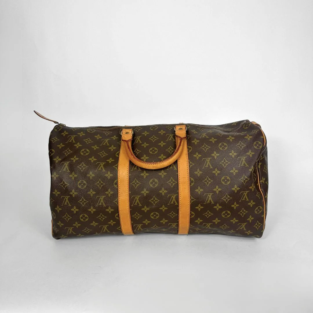 Brown monogram duffel bag with tan leather handles on a white background