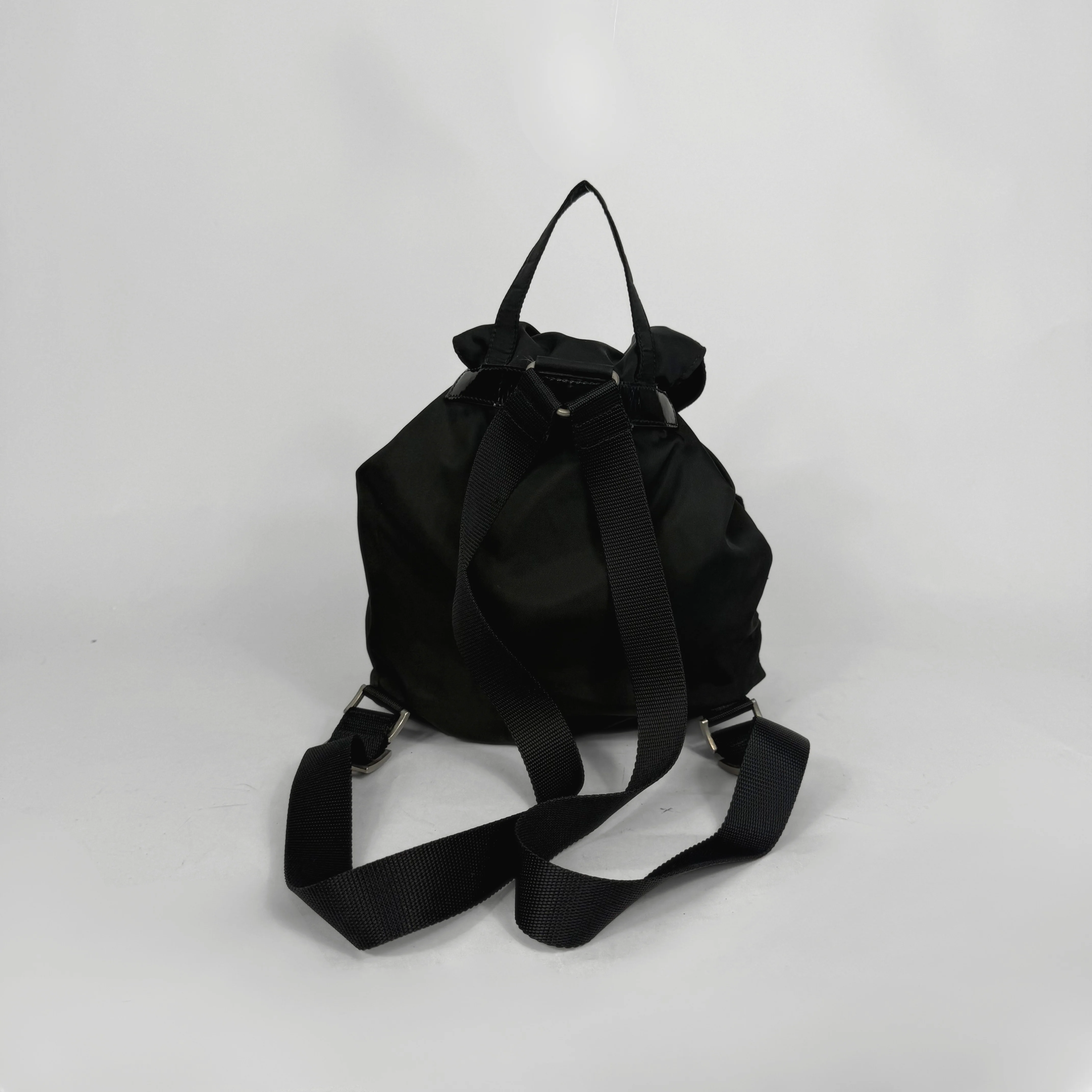 Black backpack and black ballet flats on a light gray background