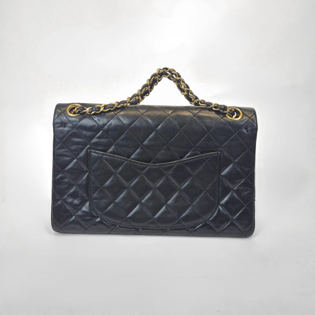 Black Chanel handbag with gold chain handle and clasp on a white background