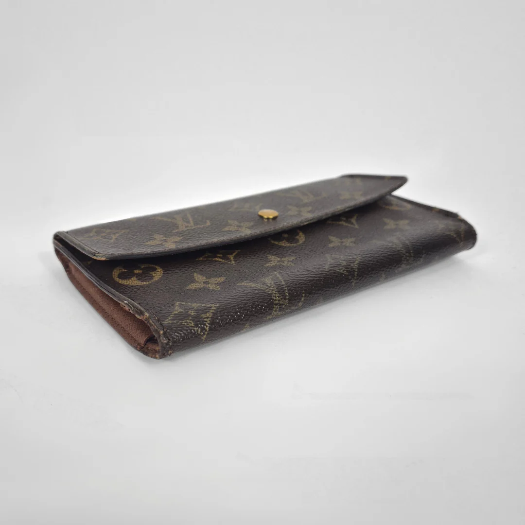 Designer wallet with monogram pattern on a light gray background