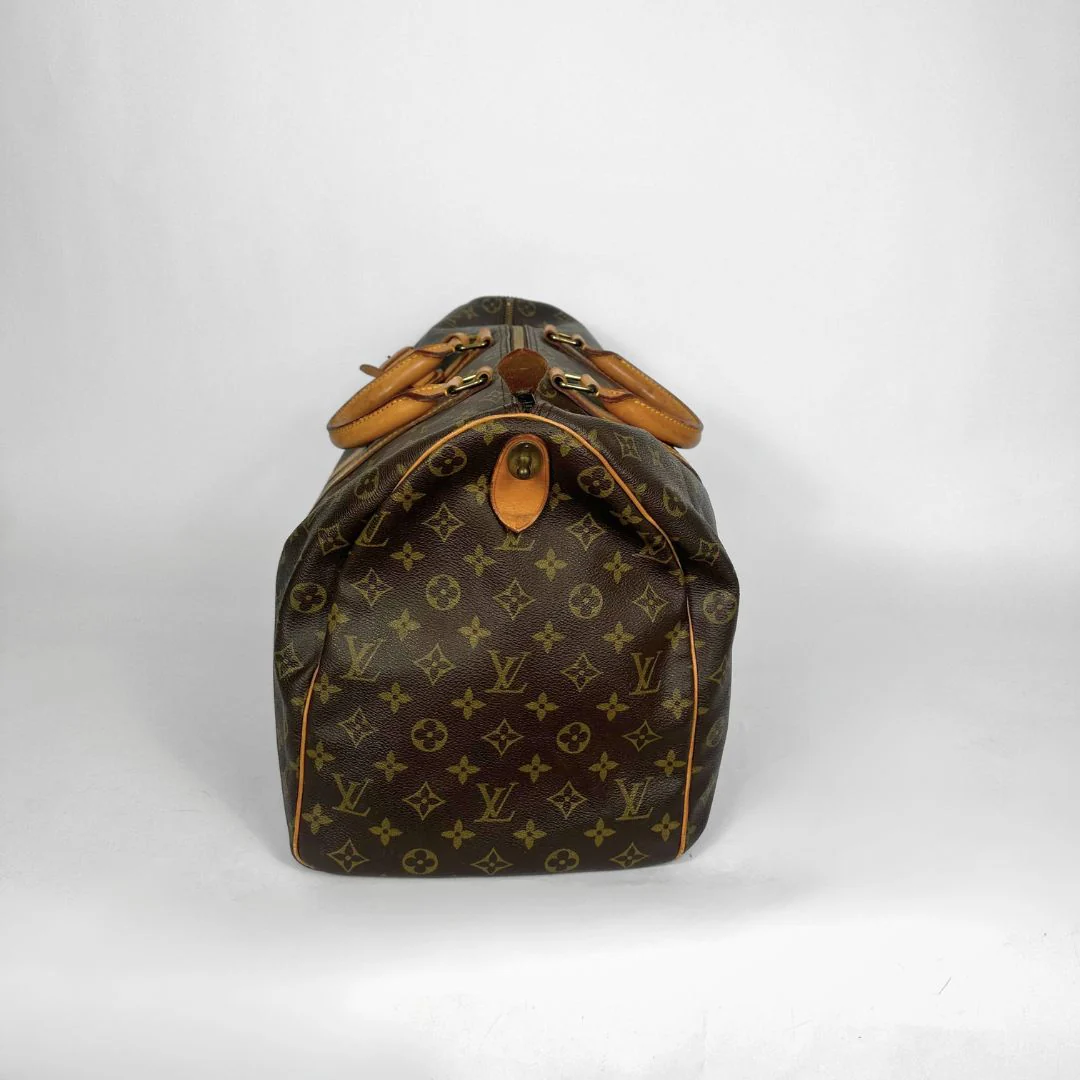 Brown monogram duffel bag with tan leather handles on a white background