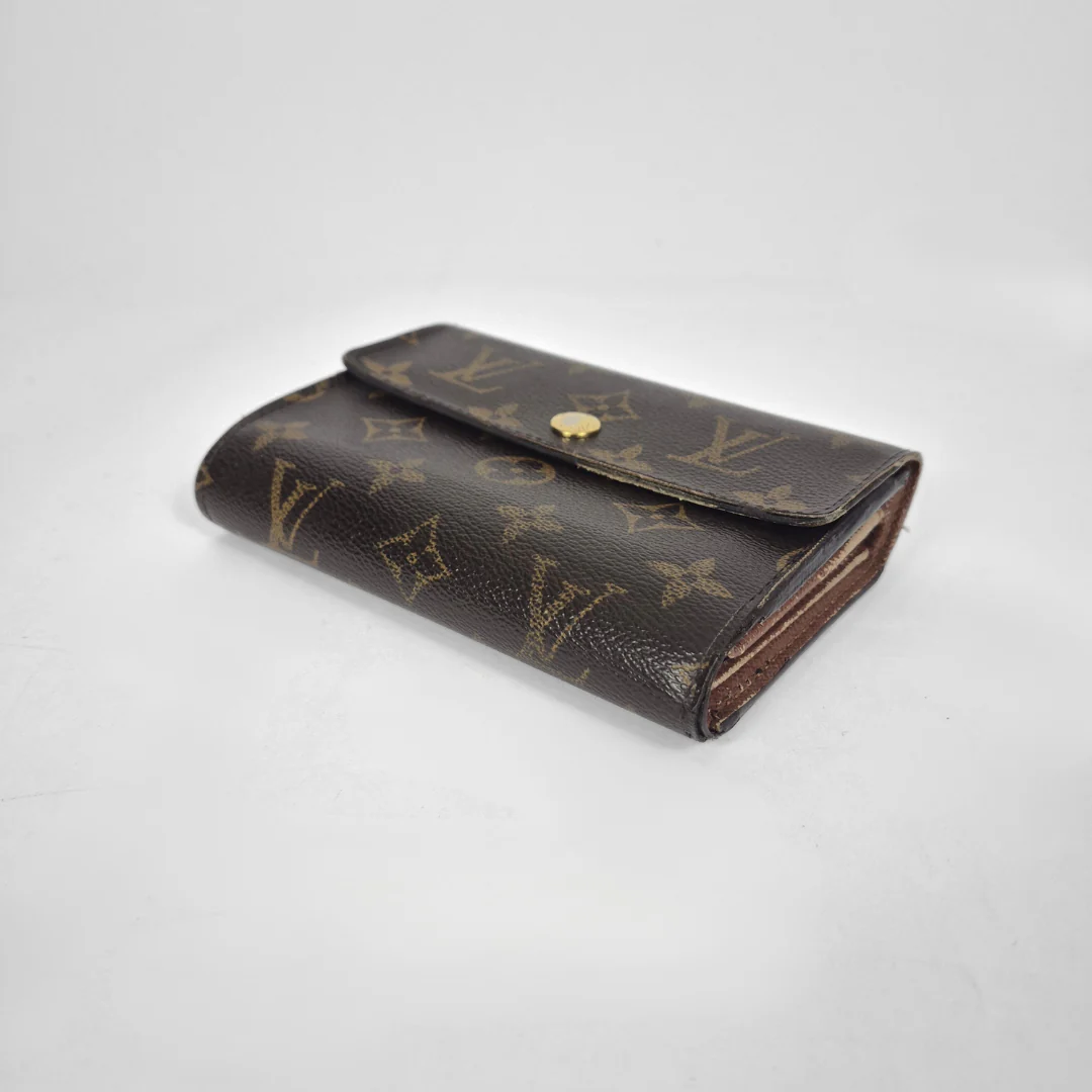 Louis Vuitton wallet with monogram pattern on a light gray background