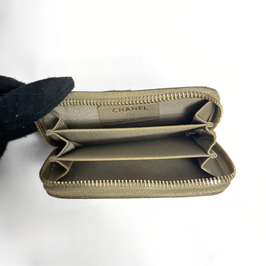 Beige Chanel wallet with gold studs on a white background