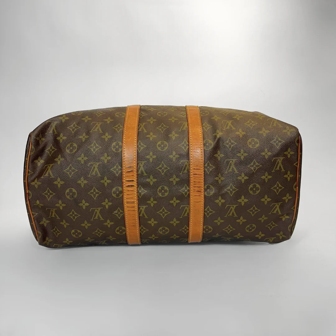 Brown travel bag with orange straps on a gray background