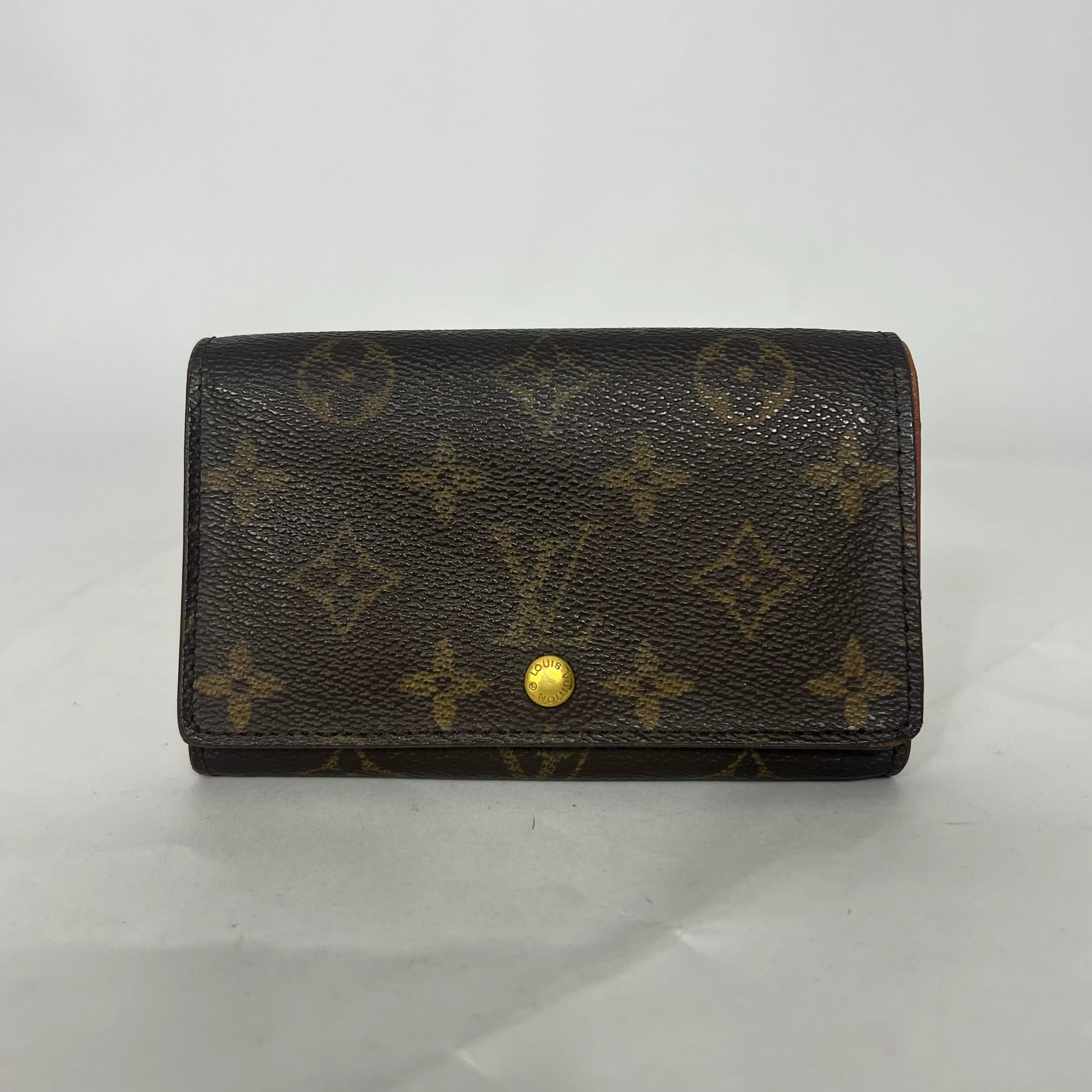 Brown wallet with gold monogram pattern on a white background