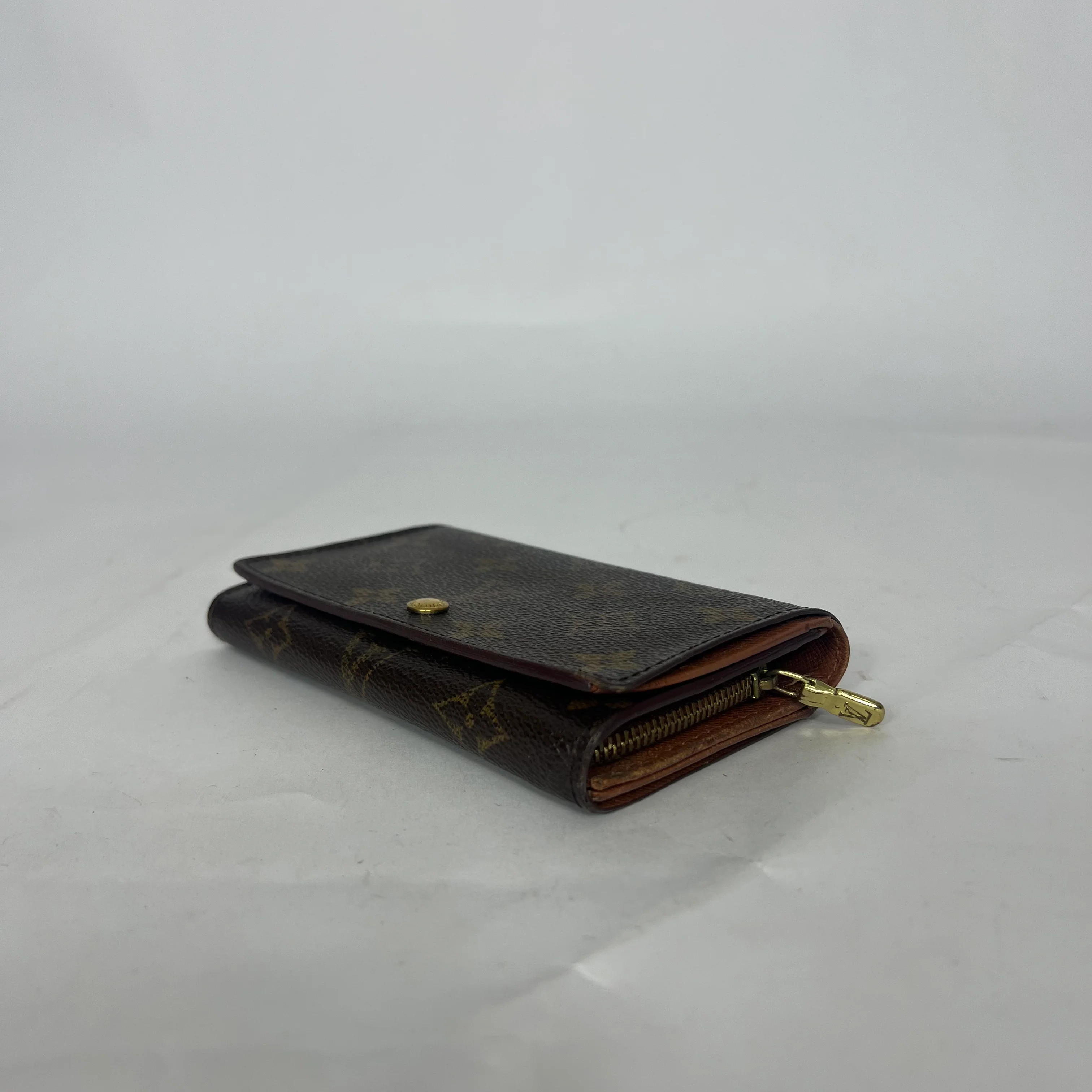 Brown wallet with gold accents on a light gray background