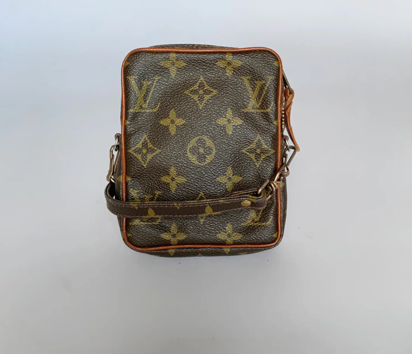 Black leather bag with brown monogram pattern on a white background